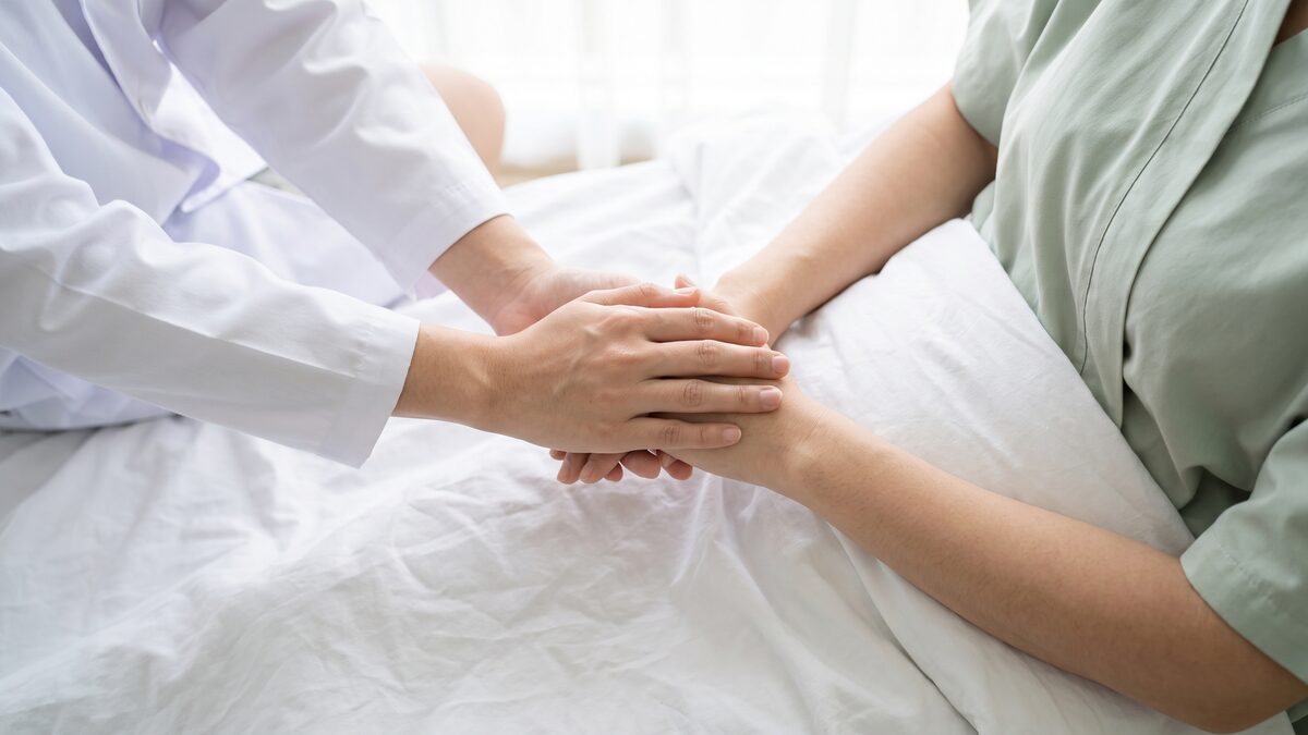 의료진이 내담자의 손을 감싸 잡고 상담하는 모습, 얼굴은 보이지 않는 익명 컷 (AI 생성 예시 이미지)