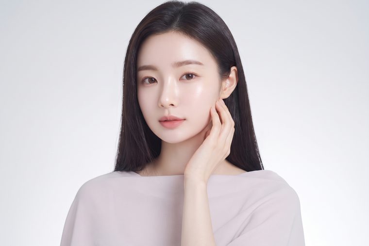 밝은 스튜디오에서 뺨과 목에 손을 얹은 가상 모델 포트레이트 (AI 생성 예시 이미지)