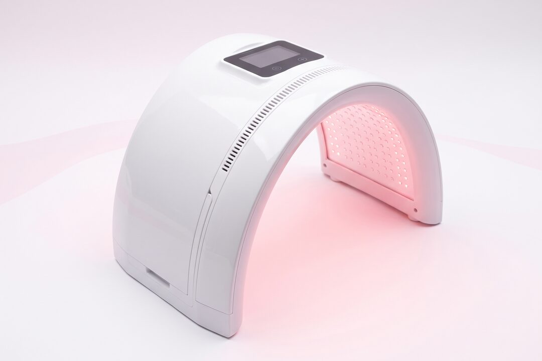 핑크 빛을 내는 아치형 LED 피부 재생 관리 장비 연출 컷 — AI 생성 예시 이미지