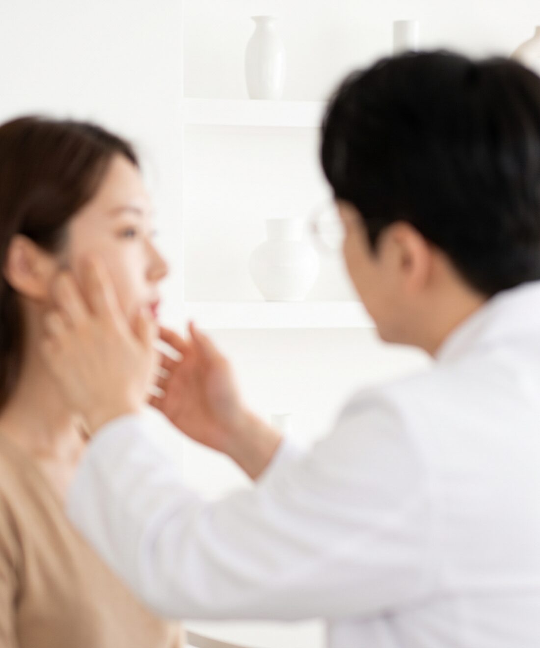 밝은 화이트 진료실에서 의료진이 고객의 얼굴 라인을 살피는 상담 장면 — AI 생성 예시 이미지