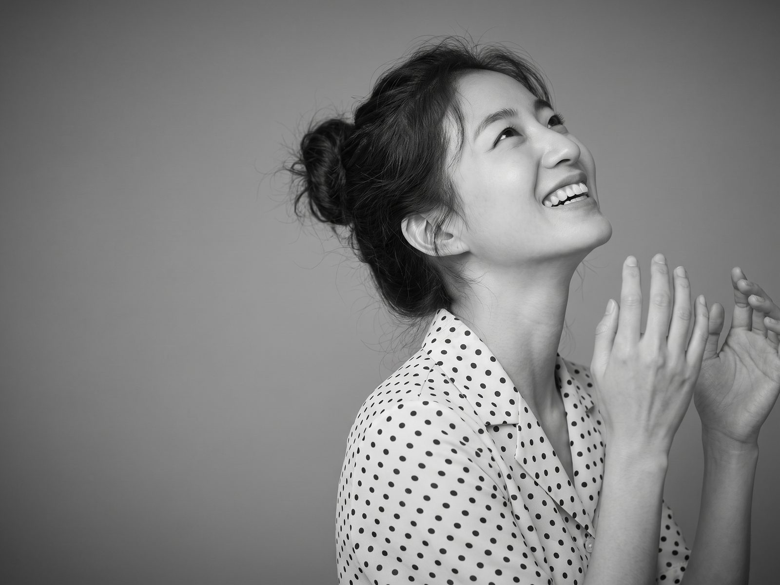 고개를 젖히고 환하게 웃는 가상 모델의 흑백 상반신 이미지 · AI 생성 예시