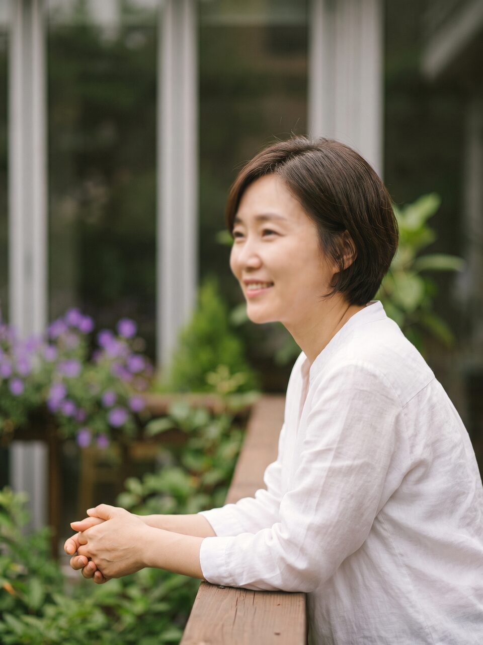 야외 테라스 난간에 손을 얹고 미소 짓는 리뷰티 의료진 인물 컷 (AI 생성 예시 이미지)