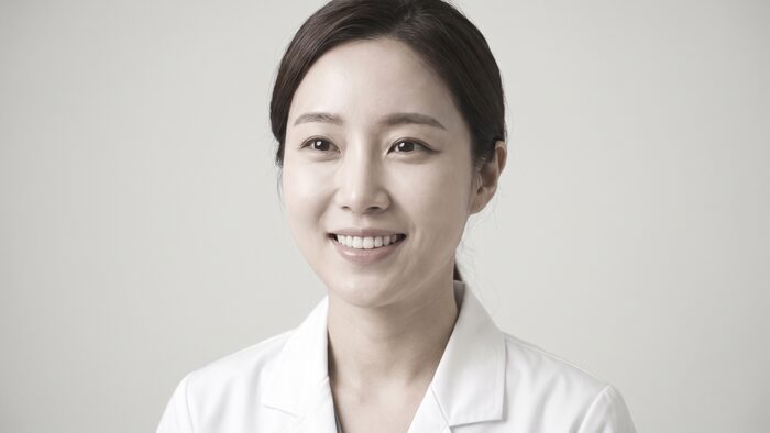 흰 가운을 걸치고 밝게 웃는 방문객 인물 컷 (AI 생성 예시 이미지)