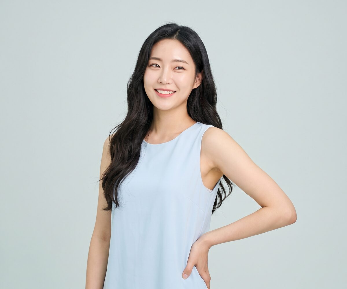 연한 하늘색 탑을 입은 여성이 편안하게 서 있는 체형 웰에이징 이미지 (AI 생성 예시)