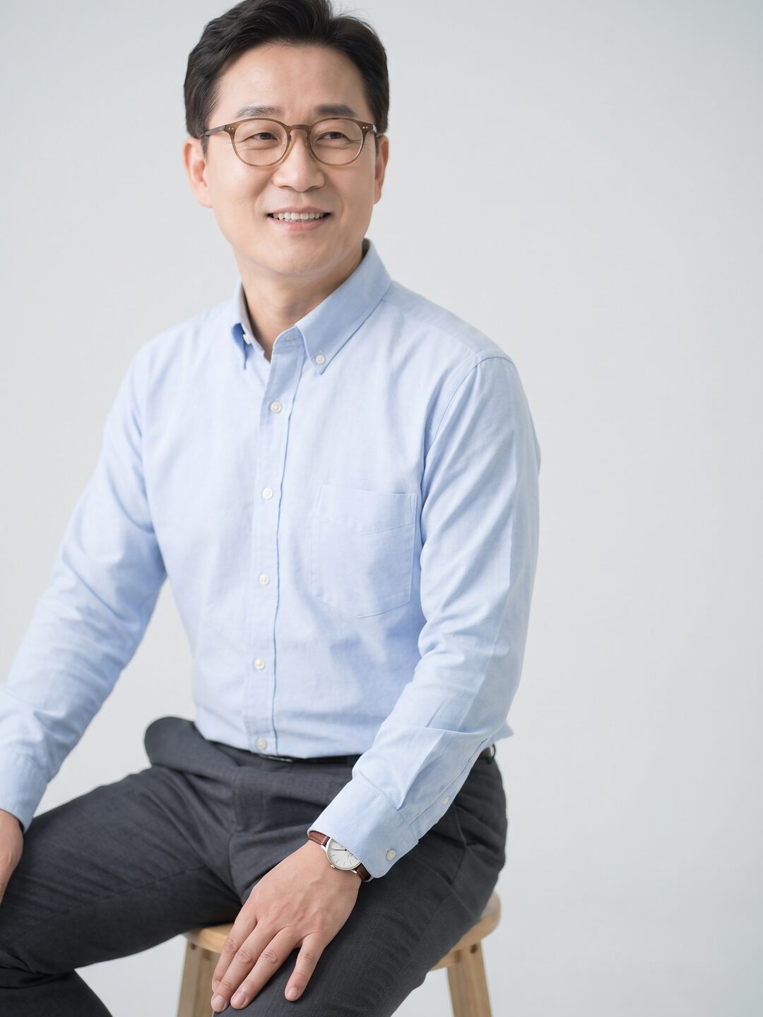 밝은 스튜디오 배경 앞 의자에 앉아 편안하게 미소 짓는 리뷰티 의료진 (AI 생성 예시 이미지)