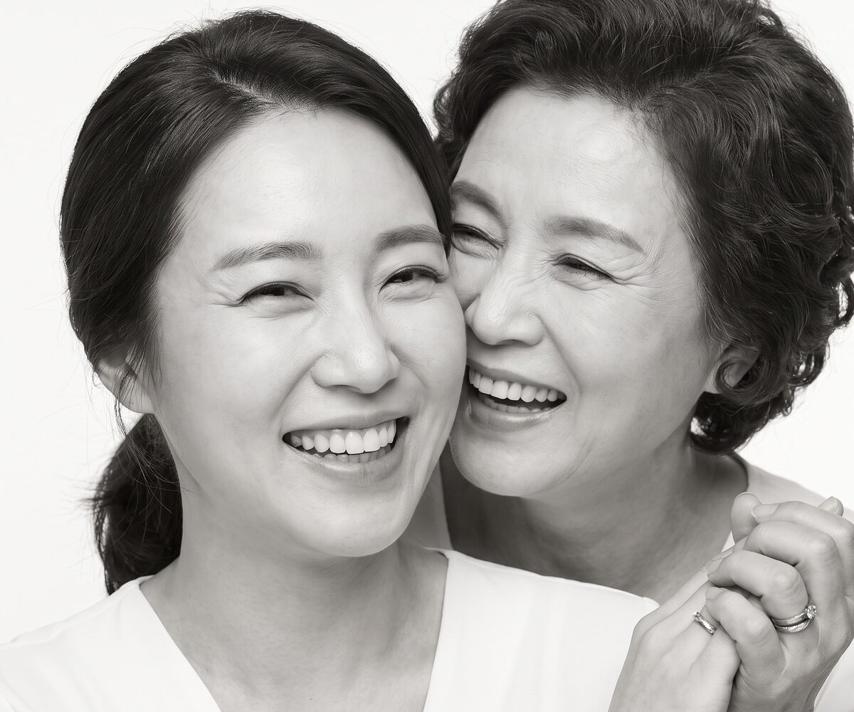 두 세대의 여성이 얼굴을 맞대고 함께 웃는 흑백 얼굴 웰에이징 이미지 (AI 생성 예시)