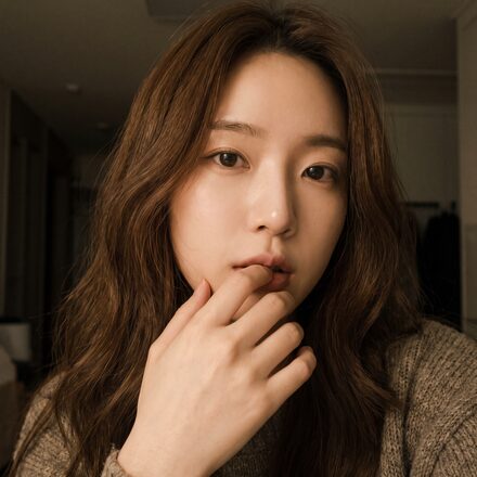 리뷰티 셀피존 - 손가락을 턱 가까이 두고 찍은 실내 셀피 컷(AI 생성 예시 이미지)