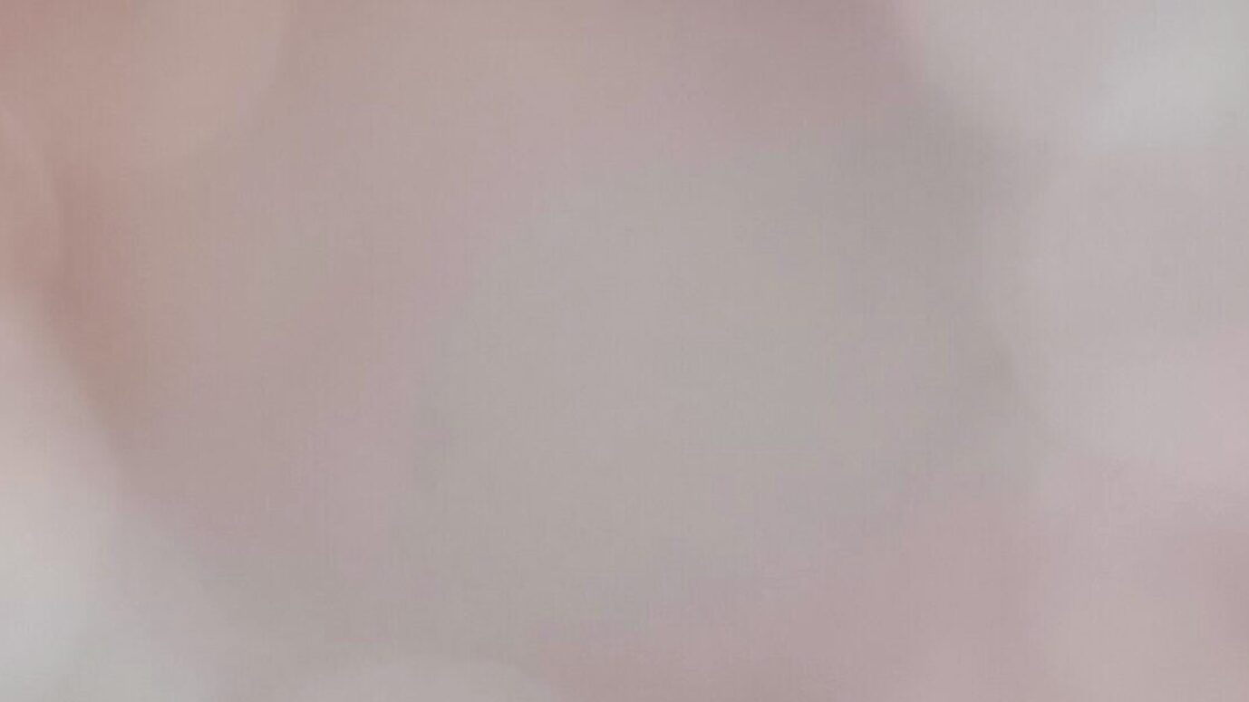 흰 벽면을 완만한 아치로 가로지르는 옅은 무지개빛 광선 곡선