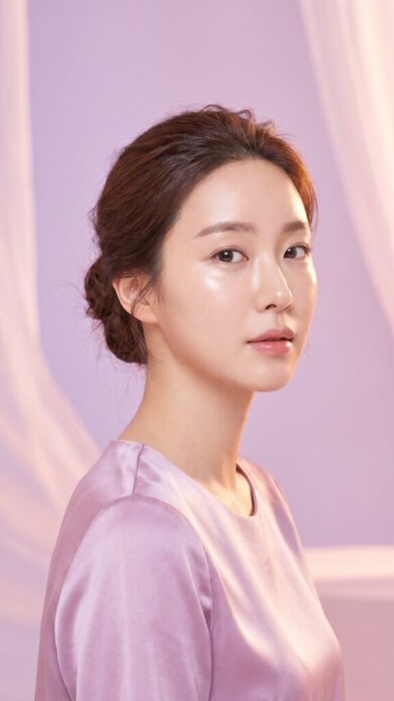 리뷰티 쇼츠 썸네일 — 긴 웨이브 머리의 여성 모델이 창가에서 촬영한 세로 컷