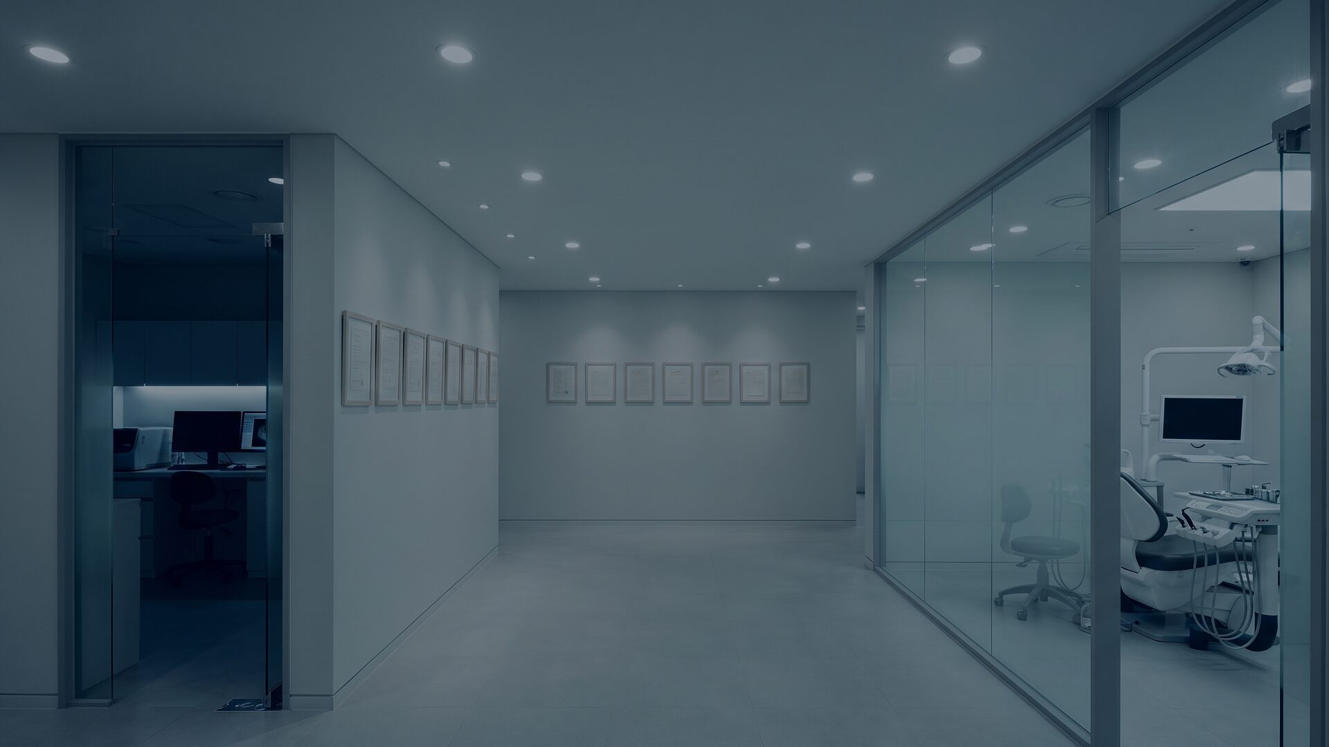 유리도어 안쪽 기공 작업실과 액자가 걸린 벽면, 유리 파티션 너머 상담 공간이 한 화면에 담긴 리뷰티치과 내부 전경